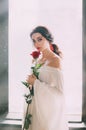 Portrait young bride woman. White medieval luxury sexy dress. Red rose in hands. Royalty Free Stock Photo