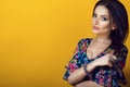 Portrait of young beautiful brunette in blue low-necked dress with bright floral print holding ends of her hear Royalty Free Stock Photo