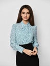 Portrait of young beautiful brunette business woman in stylish formal blouse shirt and black skirt over grey background