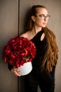 Portrait of young beautiful brunette girl with big round box of large red peony flower near wall Royalty Free Stock Photo