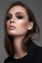 Portrait of young beautiful brunette girl with professional makeup, trendy gold eyeshadows, nude lips and natural hair.