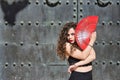 Portrait of young, beautiful, brunette woman with black top and skirt, dancing flamenco with a red fan with an old, black metal Royalty Free Stock Photo