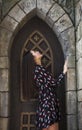 Portrait young beautiful brunette woman in dress posing against the backdrop of an old castle in the Gothic style Royalty Free Stock Photo