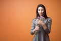 Portrait of a young beautiful brunette woman in grey dress holding violet flowers in her hands Royalty Free Stock Photo