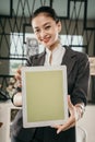 Portrait of young beautiful business woman showing her blank screen tablet to the camera and smiling Royalty Free Stock Photo