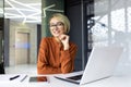 Portrait of a young beautiful business woman at the workplace inside the office, the female worker is using a laptop Royalty Free Stock Photo