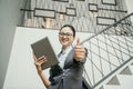 Portrait of young beautiful businesswoman holding at tablet standing in stairs office