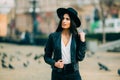 Portrait of young beautiful casual girl in jacket an black hat walking on spring city street. Royalty Free Stock Photo