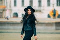 Portrait of young beautiful casual girl in jacket an black hat walking on spring city street. Royalty Free Stock Photo
