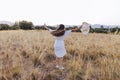 Portrait of young beautiful caucasian woman outdoors at sunset in a yellow field. wearing a modern hat and smiling. Dancing around Royalty Free Stock Photo