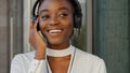 Portrait of young beautiful cheerful funny African American girl student tourist stands in headphones listening to music Royalty Free Stock Photo