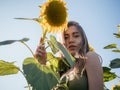 Portrait young beautiful and cheerful woman posing in field of sunflowers at sunset Royalty Free Stock Photo