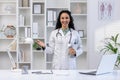 Portrait of a young beautiful clinic worker with a tablet computer in her hands, the woman smiles joyfully and looks at Royalty Free Stock Photo