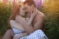 Portrait of a young beautiful couple gently embracing on a blooming field during sunset