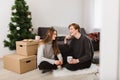 Portrait of young beautiful couple sitting on floor at home and talking to each other while decorating new year tree Royalty Free Stock Photo