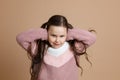 Portrait of young beautiful cute smiling girl with long dark hair in white, pink sweater standing, covering ears with