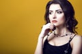 Portrait of a young beautiful dark haired concerned woman wearing black top and glass beads looking worried and thoughtful