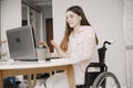 Young disabled woman in wheelchair working with laptop and tablet at home Royalty Free Stock Photo