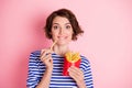 Portrait of young beautiful excited crazy hungry pretty girl bite lip eat french fries isolated on pink color background