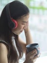 Portrait of female listen music through headphone and holding coffee cup