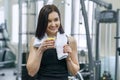 Portrait of young beautiful fitness woman in sportswear with towel, with glass of water and lemon, after fitness classes drinking Royalty Free Stock Photo