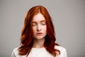 Portrait of young beautiful ginger girl with eyes closed over gray background. Royalty Free Stock Photo