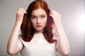 Portrait of young beautiful ginger girl over gray background with back light. Royalty Free Stock Photo