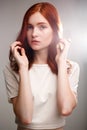 Portrait of young beautiful ginger girl over gray background with back light. Royalty Free Stock Photo