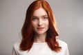 Portrait of young beautiful ginger girl over gray background with back light. Royalty Free Stock Photo