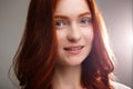 Portrait of young beautiful ginger girl over gray background with back light. Royalty Free Stock Photo