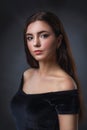 Portrait of a young beautiful girl in a black dress. Model with dark hair posing near the wall