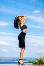 Portrait of a young beautiful girl in a black skirt and a bra posing on a background of blue sky Royalty Free Stock Photo