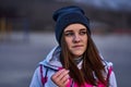 Portrait of a young beautiful girl with dark brown hair in a sports hat and jacket in the first rays of the morning rising sun