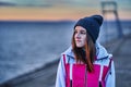 Portrait of a young beautiful girl with dark brown hair in a sports hat and jacket in the first rays of the morning