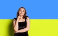 Portrait of young beautiful girl with dreamy and thoughtful facial epression over blue and yellow ukrainian