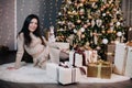 portrait of a young, beautiful girl in a dress near the Christmas tree with a bunch of gifts