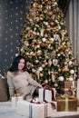 portrait of a young, beautiful girl in a dress near the Christmas tree with a bunch of gifts