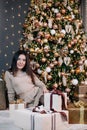 portrait of a young, beautiful girl in a dress near the Christmas tree with a bunch of gifts