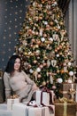 portrait of a young, beautiful girl in a dress near the Christmas tree with a bunch of gifts