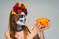 Portrait of young beautiful girl with fearful halloween skeleton makeup with a wreath Katrina Calavera made of flowers on her head