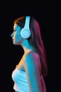 Portrait of young beautiful girl in headphones isolated over dark background. Royalty Free Stock Photo