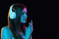 Portrait of young beautiful girl in headphones isolated over dark background. Royalty Free Stock Photo