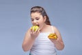 Portrait of a young beautiful girl holding a red Apple in one hand and a hamburger in the other on a white background .A true
