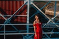 Portrait of a young beautiful girl with long brown hair, in a long red dress, the time of year. A girl walks on the bridge