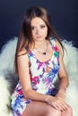 Portrait of a young beautiful girl with long hair in a white dress with flowers in red Slippers in the Studio on a black Royalty Free Stock Photo