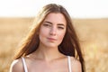 Portrait of the young beautiful girl posing against the background of the wheat field in the warm solar morning Royalty Free Stock Photo