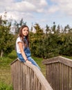 portrait of a young beautiful girl posing on the old wood bridge in green autumn farm Royalty Free Stock Photo