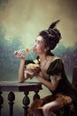 Portrait of young beautiful girl , princess in retro dress eating noodles with dreamy face against dark vintage