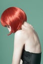 Portrait of a young beautiful girl with red short hair in the studio on a green background