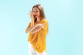 Portrait of young beautiful girl, showing direction, posing isolated over blue studio background. Talking secrets